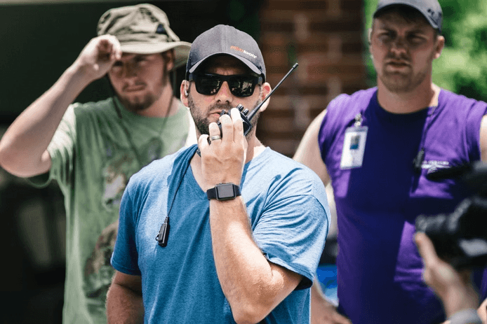 Adam Drake coordinating a film set over a walkie-talkie
